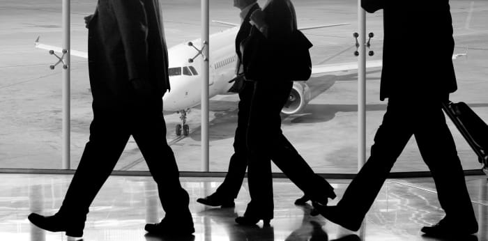 Business professionals walking through airport gate.