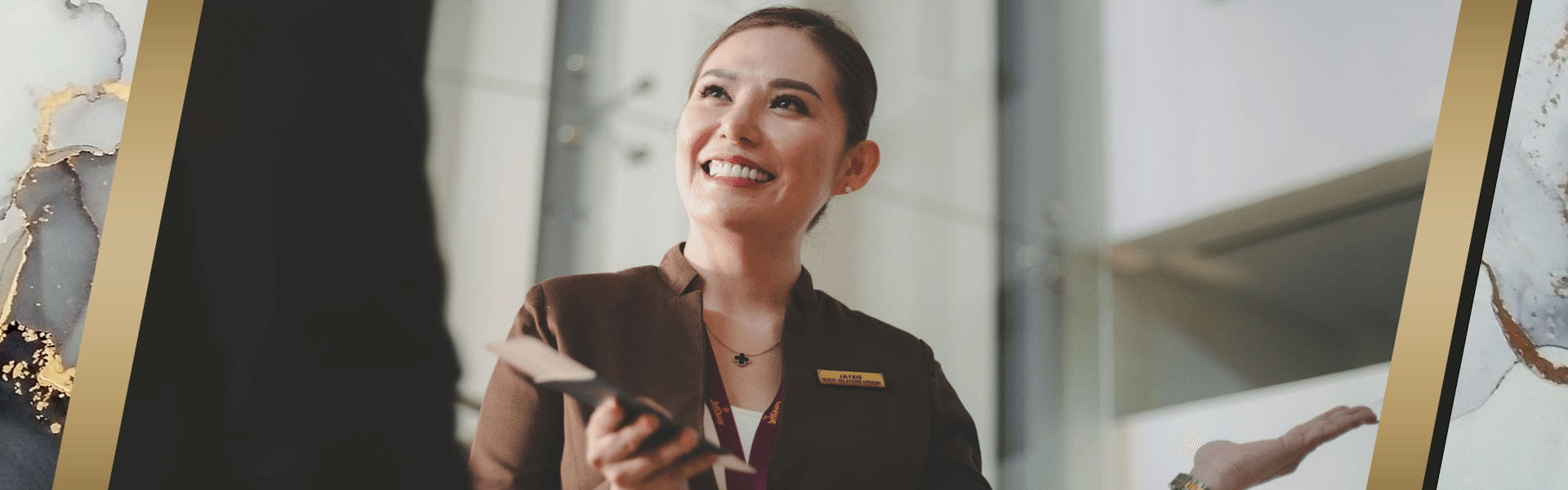 Airline ground staff smiling while assisting a passenger.