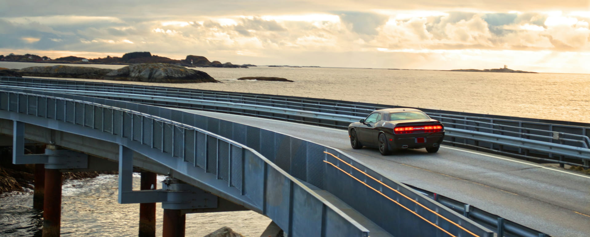 Black car driving on a coastal road.