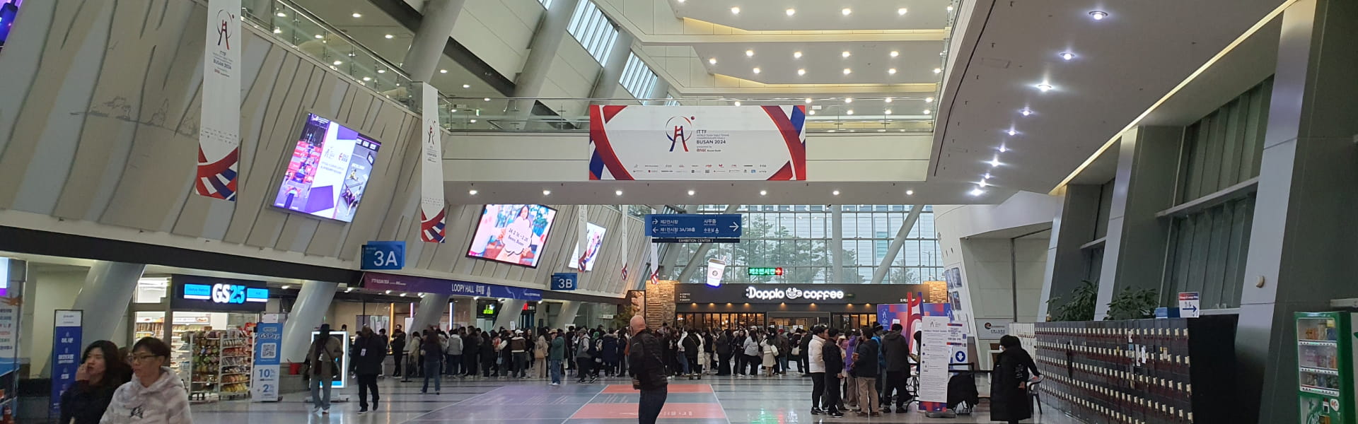 People gathered near a sign with GroundK written on it under the 2024 Busan World Table Tennis Championships banner.