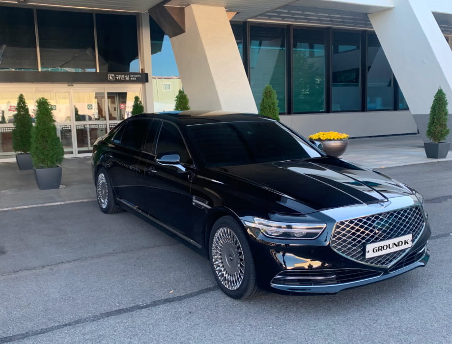 Black luxury sedan parked with a GroundK logo license plate.