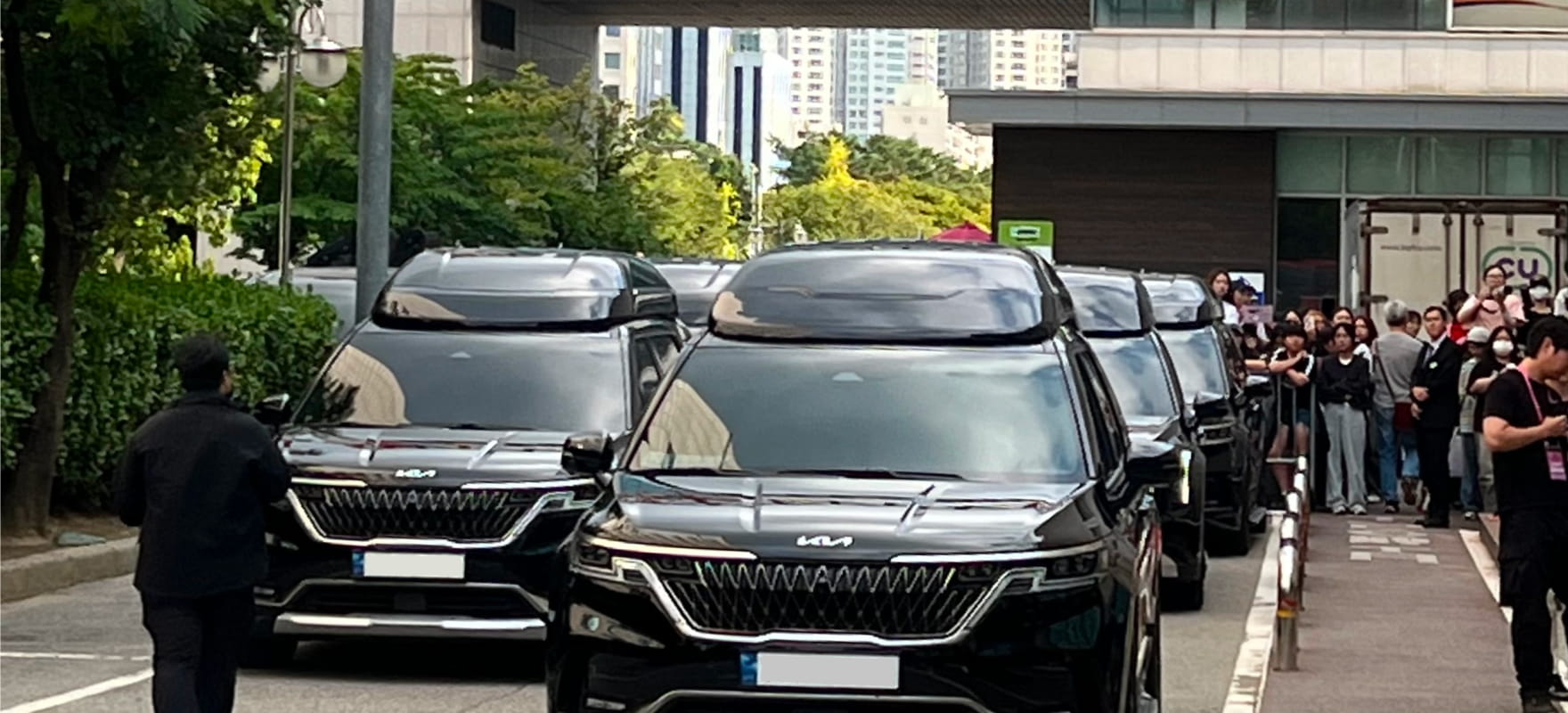 A line of black luxury protocol vans stationed along the crowd of fans and media at the 2024 Seoul International Drama Awards venue.