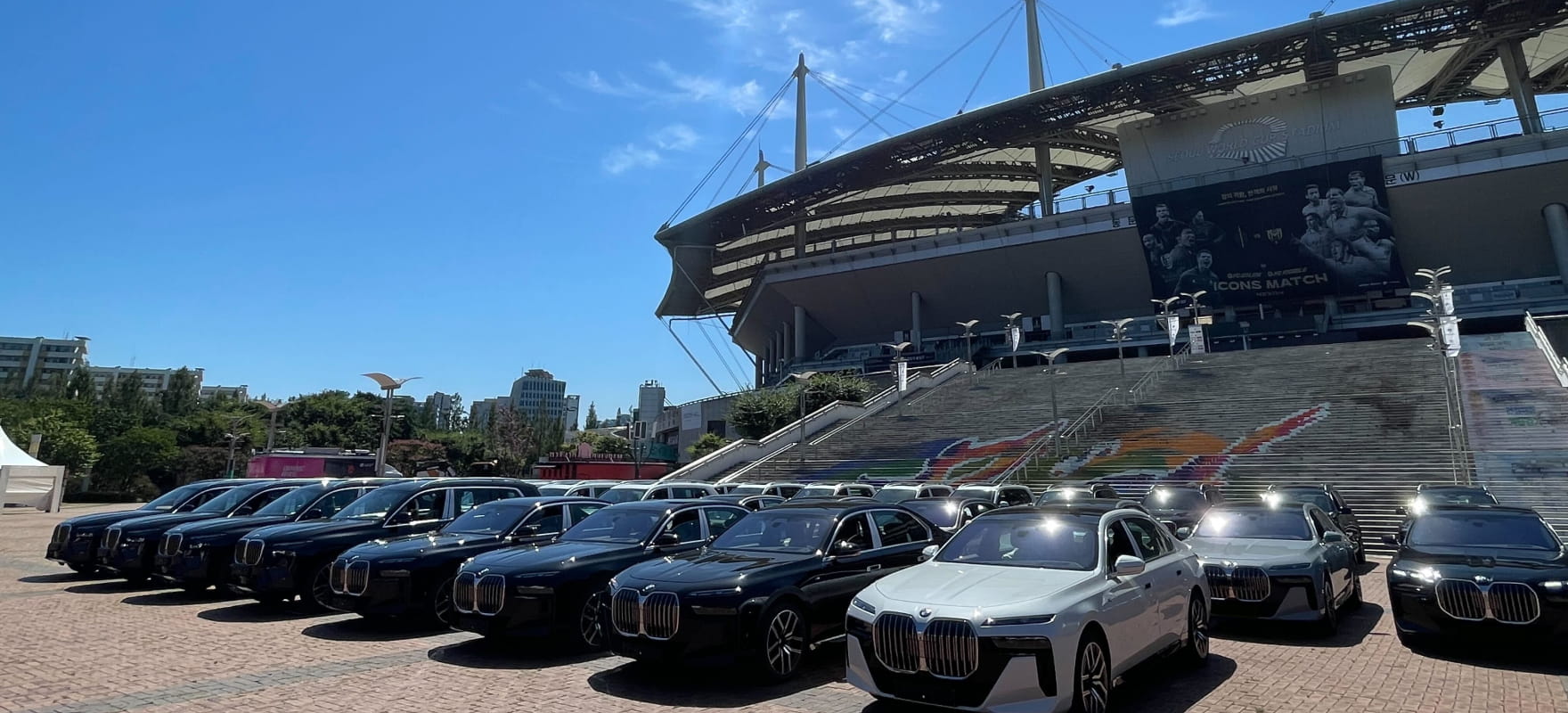 A massive fleet of black and white BMW luxury sedans parked in front of the Seoul World Cup Stadium for the 2025 ICONS Match.