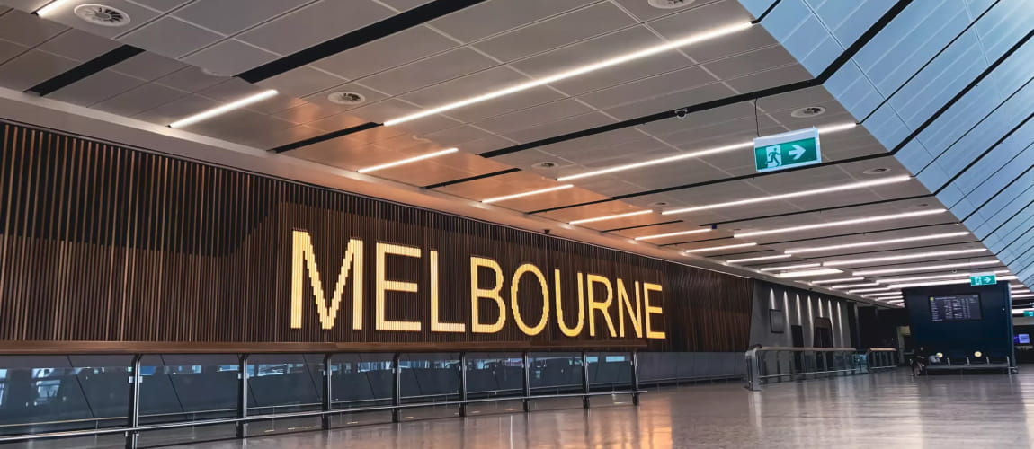 Inside Melbourne Airport terminal with prominent signage, ideal for luxury transfer services.