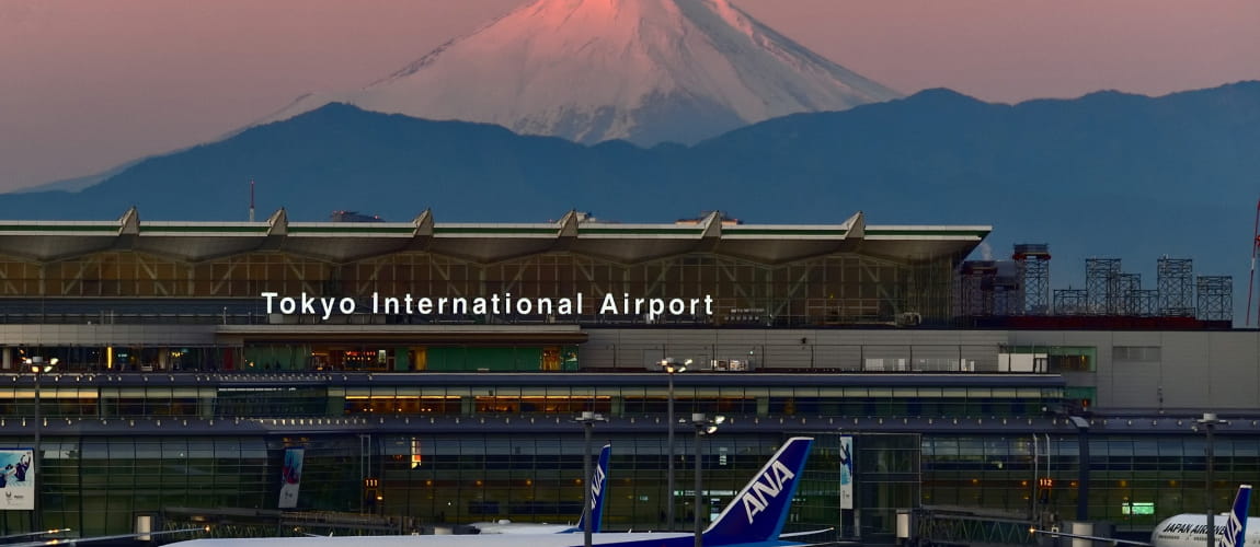 Sunset view of Tokyo International Airport and Mount Fuji, showcasing premium transfer options.