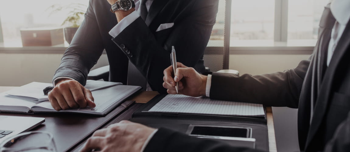 Business people in suits signing an important contract at a desk.