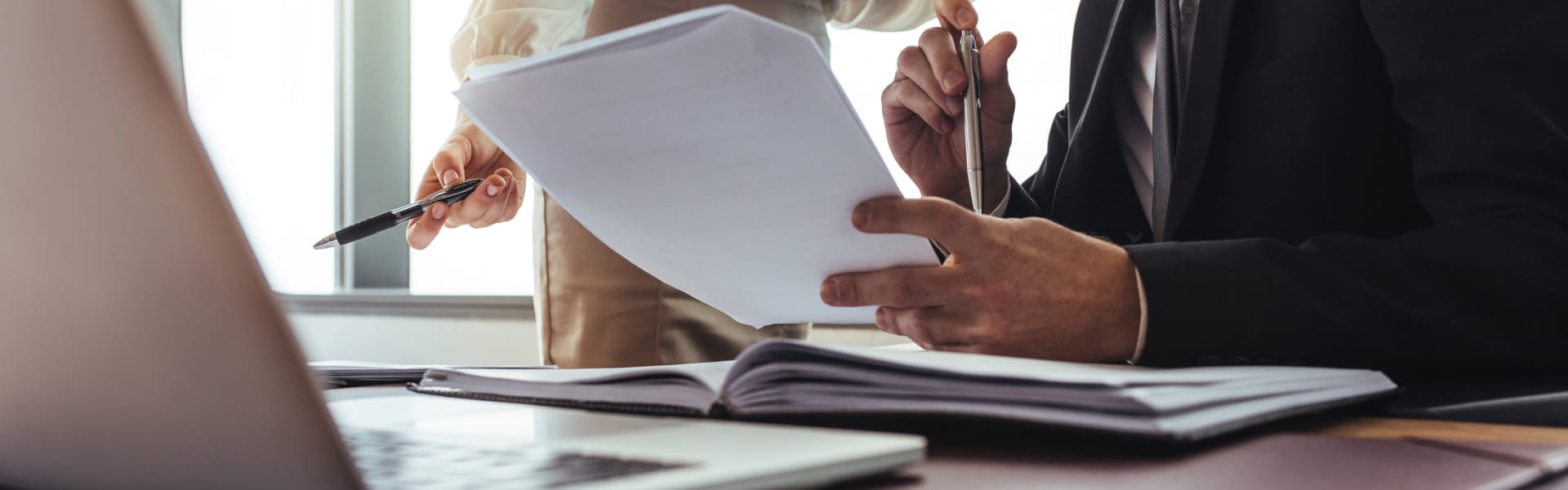 Man and woman reviewing documents on a desk, upper body view.