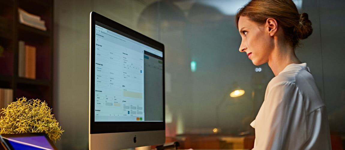 A woman working at a desk, looking at a monitor.