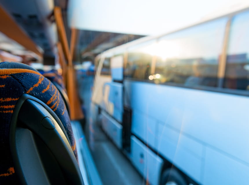 Sitting on an airport shuttle bus looking out the window at another parked shuttle bus.